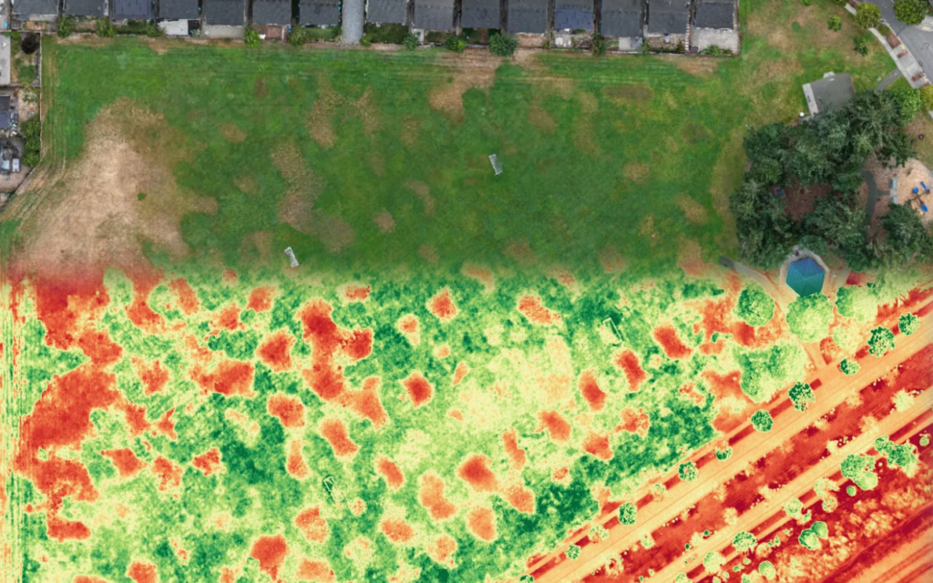 Drone mapping services plant health analysis: athletic field orthomosaic with a VARI stress overlay, where red shows turf under stress from compaction, irrigation, or disease.